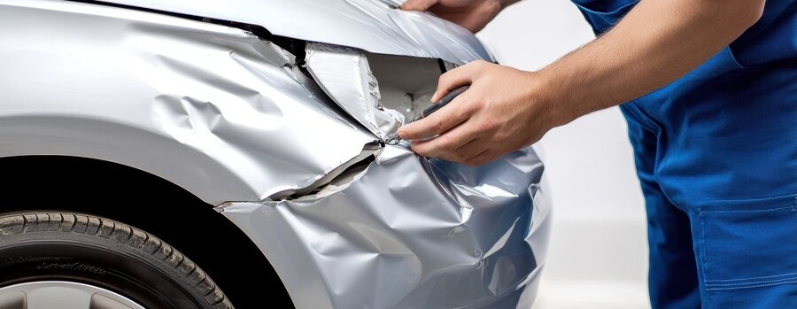 Mechanic repairing a dented luxury tesla car at an auto body repair shop